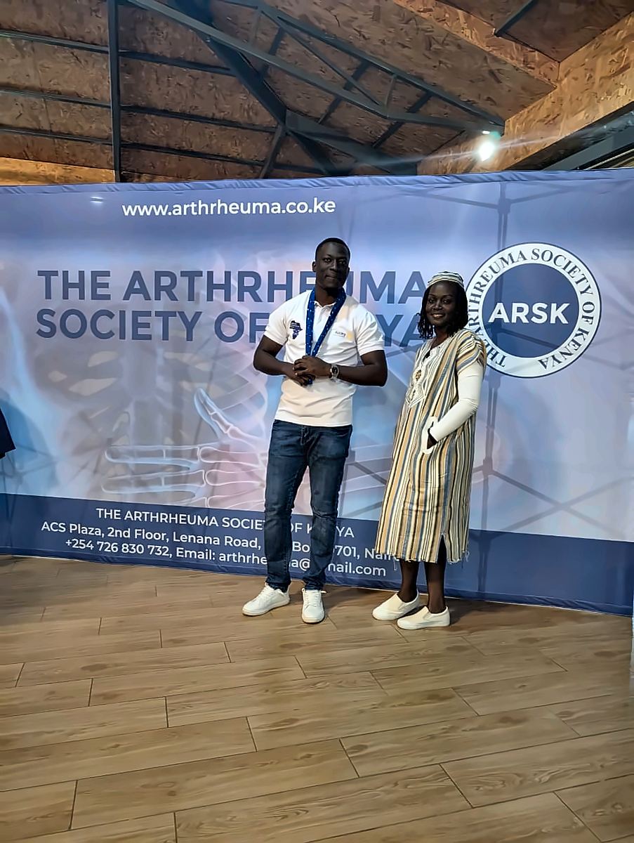 Two people in front of the Arthrheuma Society of Kenya backdrop