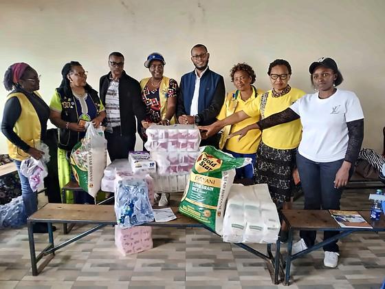 Community members and partners in yellow vests with donated rice, tissue and bottled water
