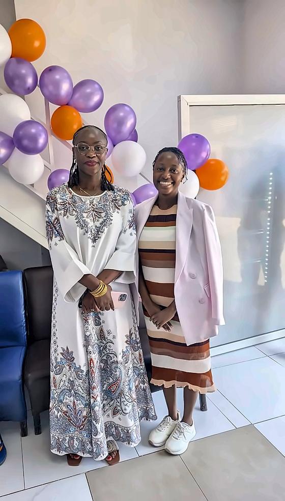 Two women in front of purple, white and orange balloons