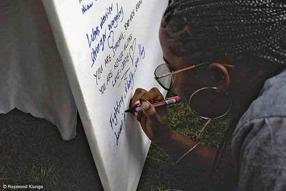 A community member writing a message on the World Lupus Day pledge wall