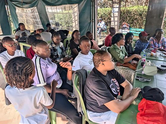 Members talking around a table under the tent at an LFA community meetup